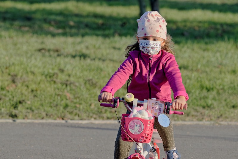 Kind mit Maske auf Velo