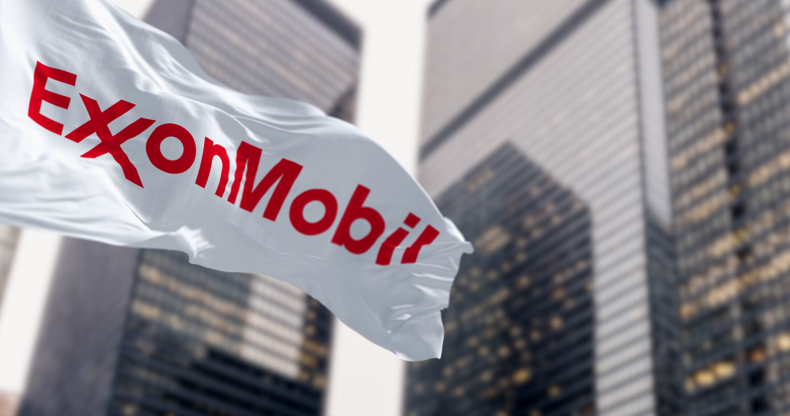 ExxonMobil flag waving in the wind in a financial district