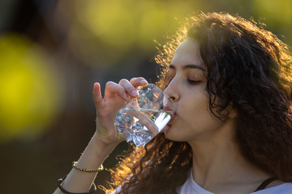 Girl drinking water from glass in park