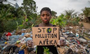 Young black african girl holding a sign written: stop pollution in Africa