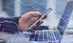 Double exposure of man's hands holding and using a phone and financial graph drawing. Analysis concept.